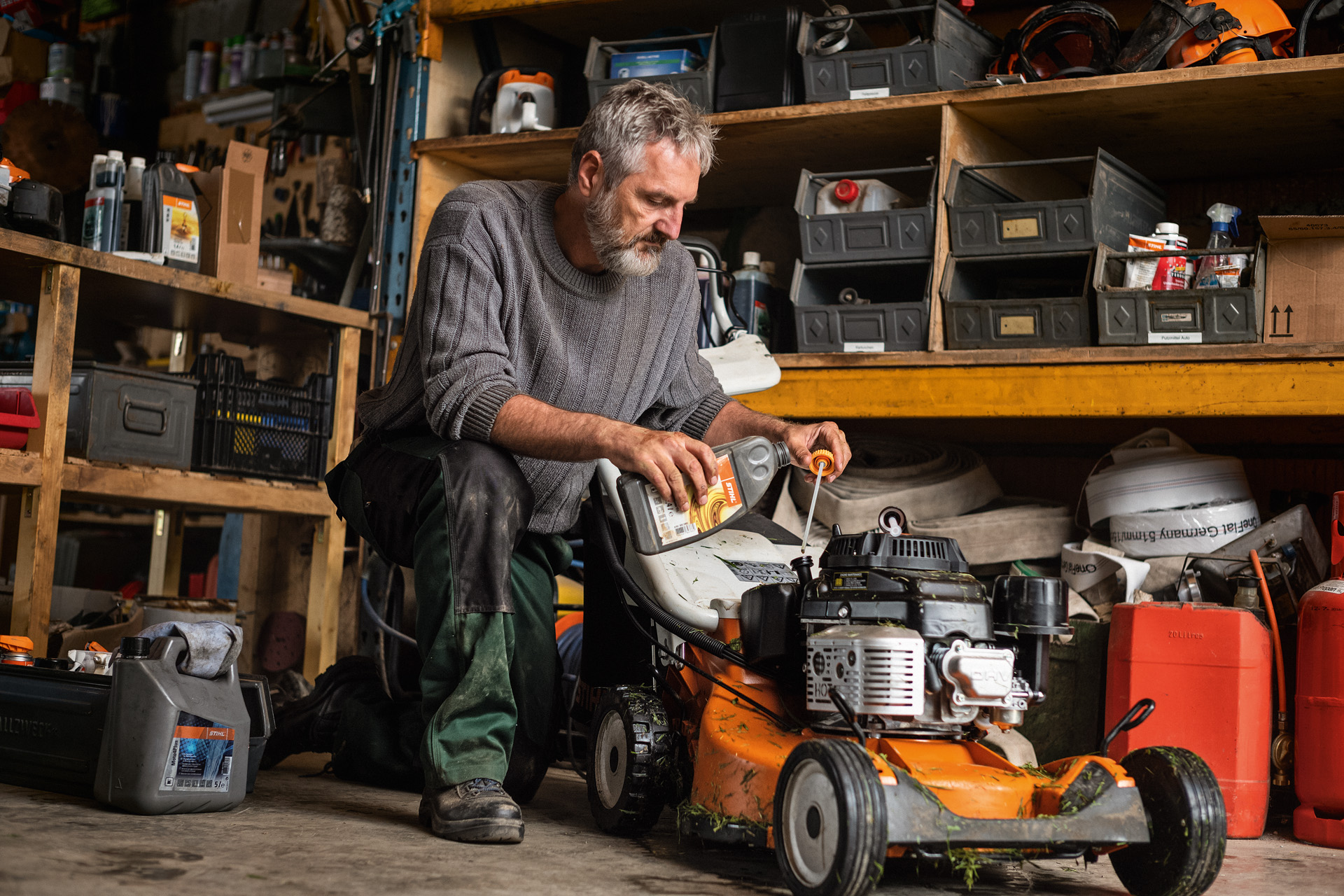 Čovek u garaži održava svoju STIHL benzinsku kosačicu RM 756