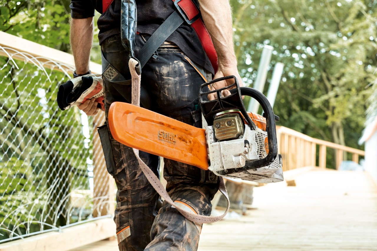 Čovek u zaštitnoj odeći nosi benzinsku lančanu testeru STIHL MS 261 sa zaštitom za lanac.