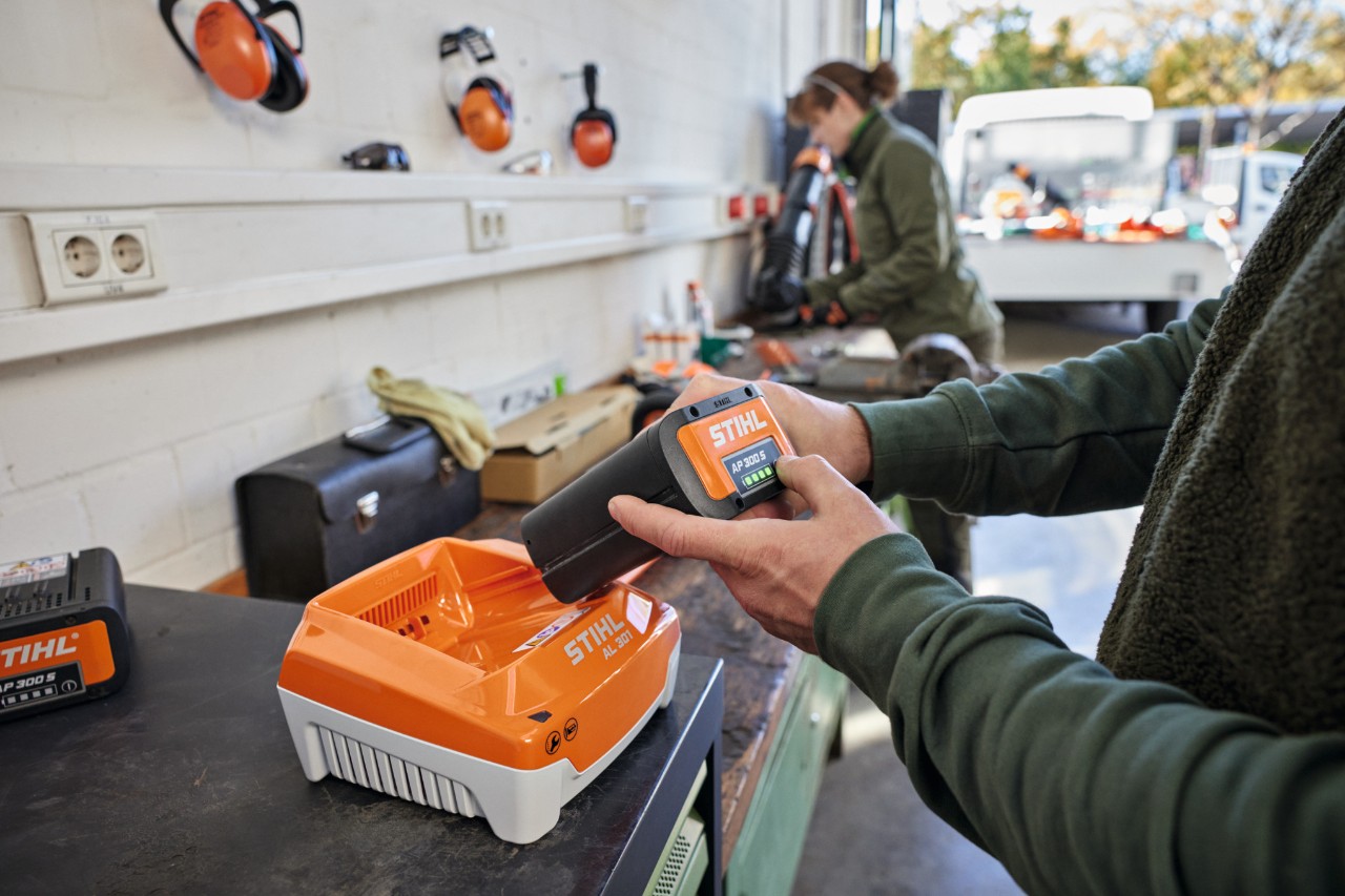 Osoba postavlja bateriju STIHL AP 300 S u uređaj za brzo punjenje STIHL AL 301
