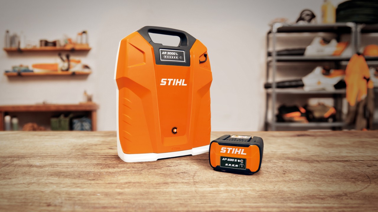 Radionica sa baterijom STIHL AR 3000 L za nošenje na leđima i baterijom STIHL AP 500 S na drvenom stolu  