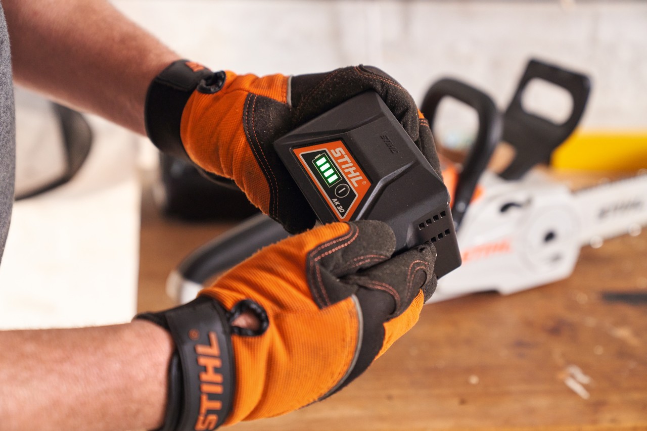 Ruke u STIHL radnim rukavicama drže STIHL litijum-jonsku bateriju