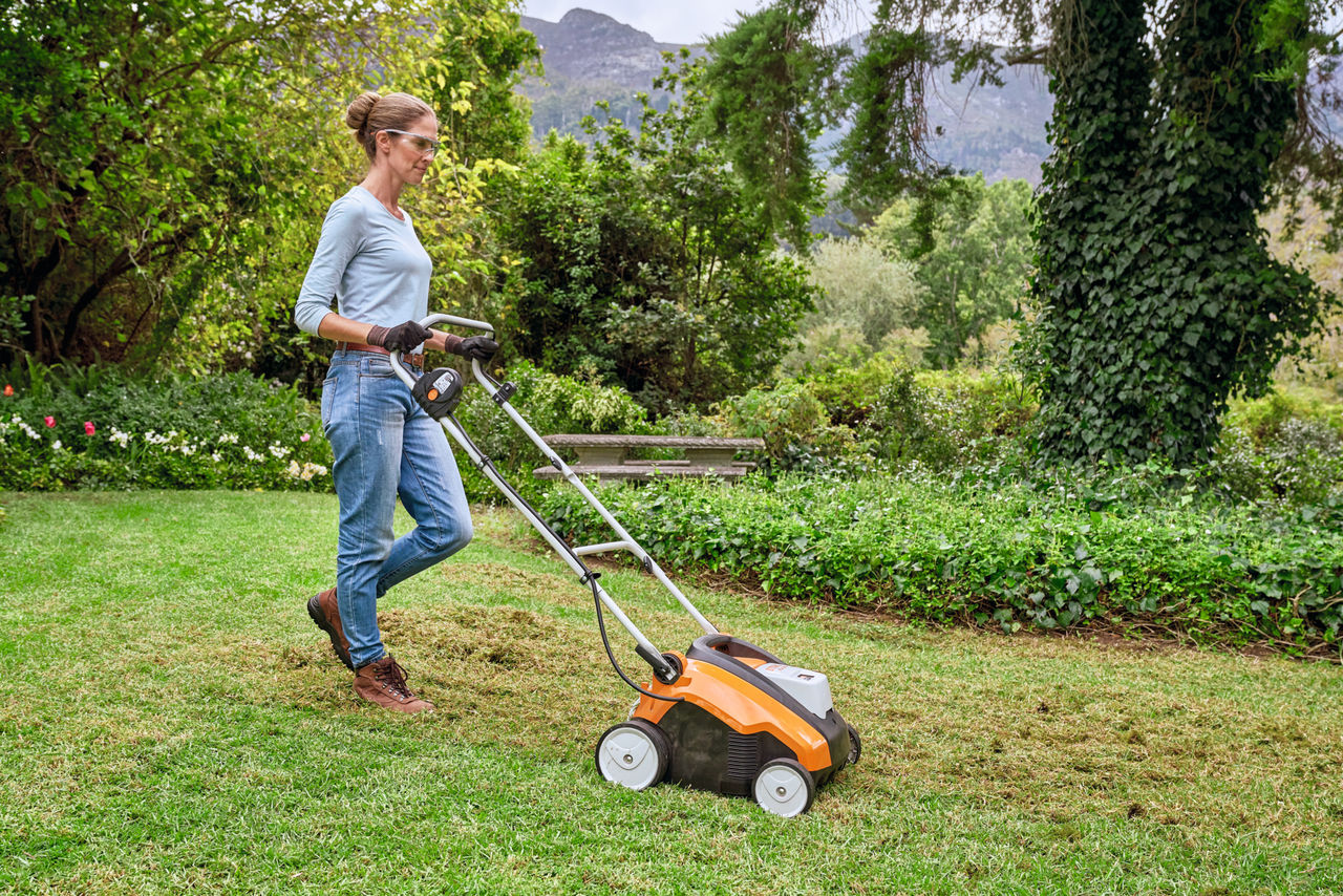 Žena sa zaštitnim naočarama i radnim zaštitnim rukavicama kosi livadu koristeći STIHL kosačicu trave